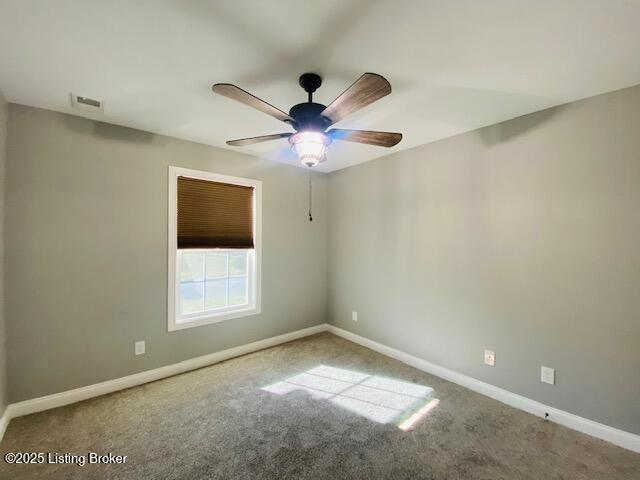 carpeted empty room with visible vents, baseboards, and ceiling fan