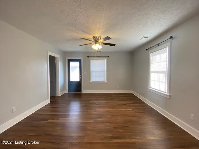 empty room with a textured ceiling, dark hardwood / wood-style flooring, and ceiling fan