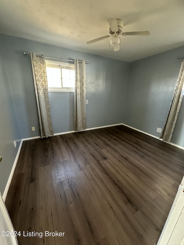 empty room featuring a textured ceiling, ceiling fan, and dark hardwood / wood-style floors