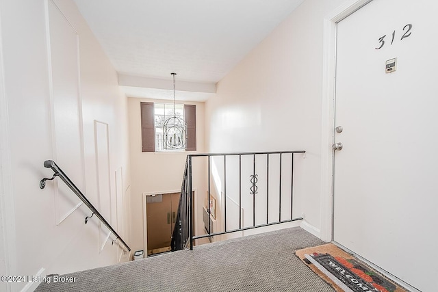 stairway with carpet floors and a notable chandelier