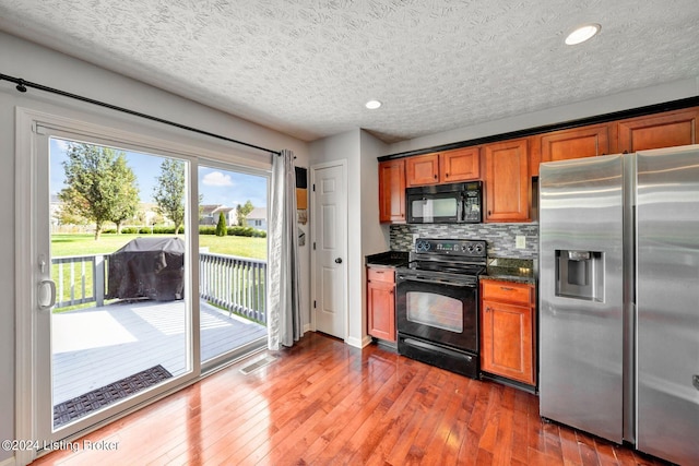 kitchen with black appliances, dark hardwood / wood-style flooring, backsplash, and a textured ceiling