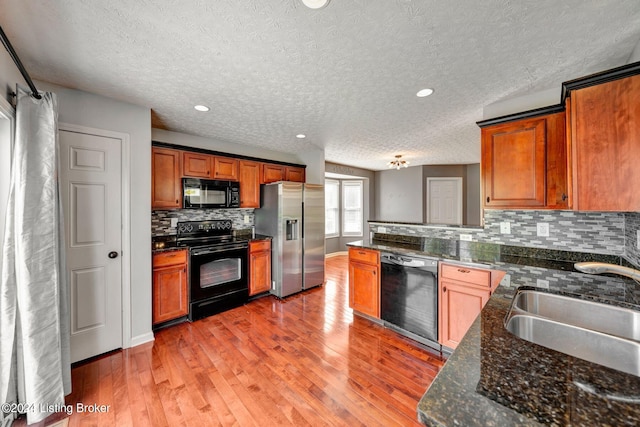 kitchen featuring tasteful backsplash, a textured ceiling, sink, black appliances, and hardwood / wood-style floors