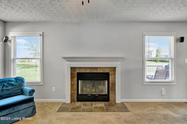 interior space with a textured ceiling, carpet floors, and a tiled fireplace