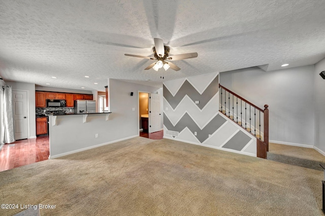 unfurnished living room featuring dark colored carpet, ceiling fan, and a textured ceiling