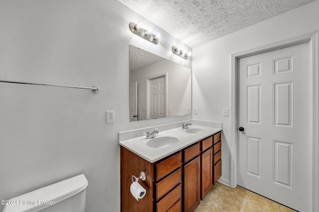 bathroom featuring tile patterned floors, vanity, a textured ceiling, and toilet