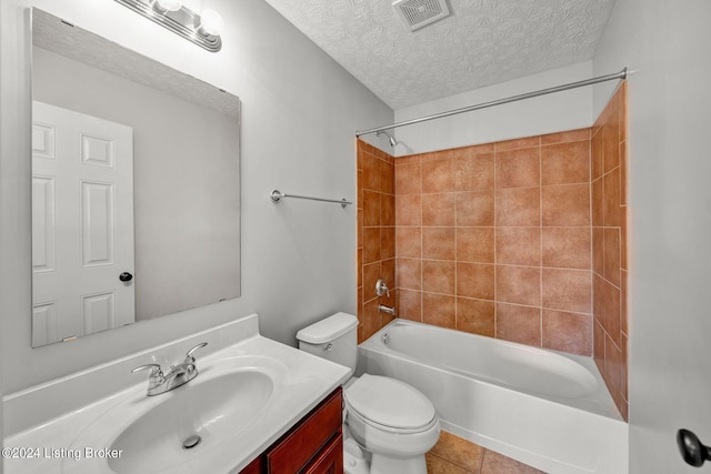 full bathroom with vanity, tile patterned floors, tiled shower / bath combo, toilet, and a textured ceiling