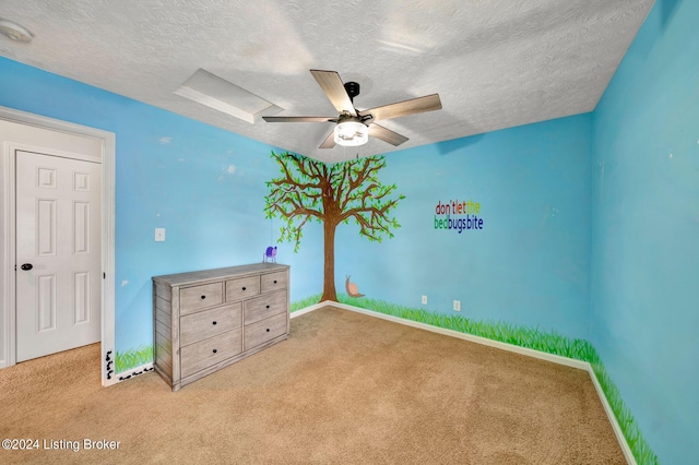 unfurnished bedroom with ceiling fan, a textured ceiling, and light carpet