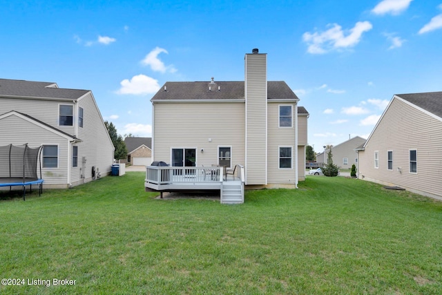 rear view of house featuring a lawn, a trampoline, and a deck