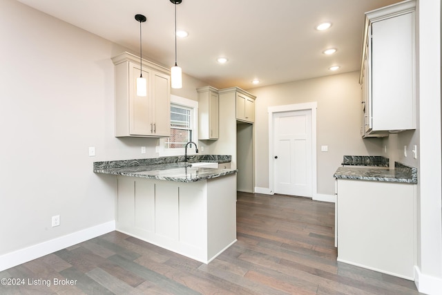 kitchen with sink, hanging light fixtures, dark wood-type flooring, and dark stone countertops