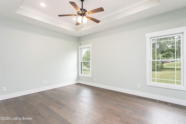 empty room with dark hardwood / wood-style flooring, ceiling fan, and a raised ceiling