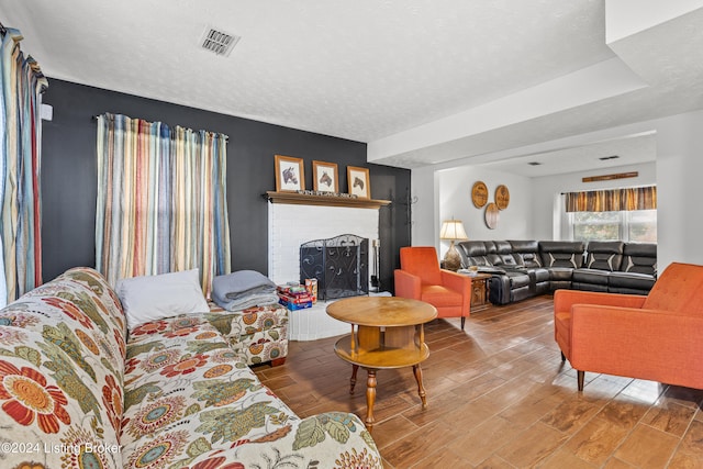 living room featuring a fireplace, wood-type flooring, and a textured ceiling