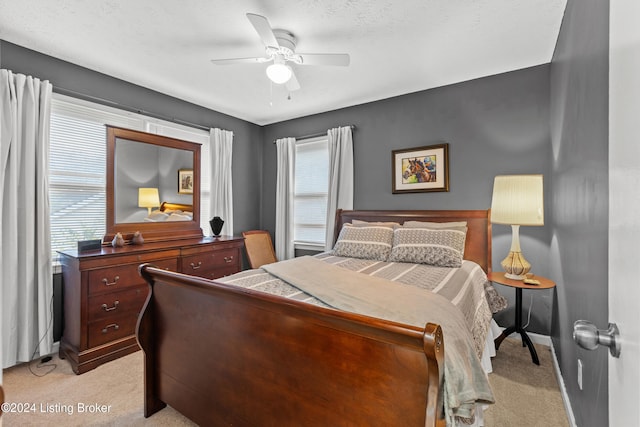 bedroom with light carpet, ceiling fan, and a textured ceiling