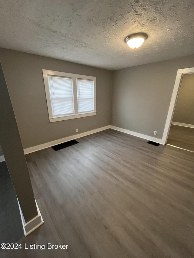 spare room with a textured ceiling and dark wood-type flooring