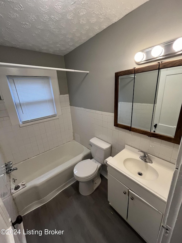 full bathroom featuring vanity, toilet, a textured ceiling, tile walls, and wood-type flooring