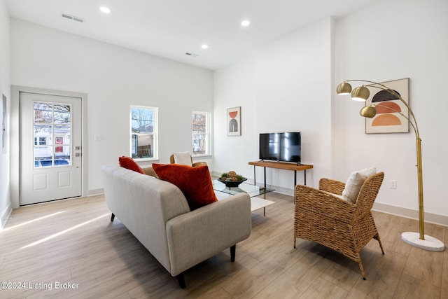 living room featuring a high ceiling and light wood-type flooring