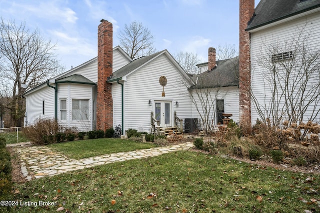 rear view of property with a lawn and central air condition unit