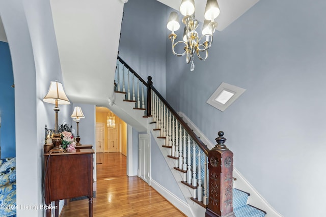 staircase with hardwood / wood-style flooring and an inviting chandelier