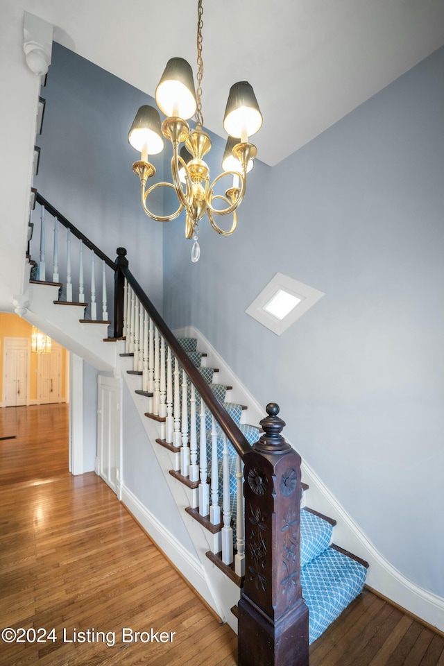 staircase featuring a chandelier and wood-type flooring