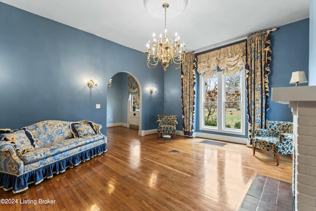 living area featuring hardwood / wood-style flooring, a fireplace, and a chandelier