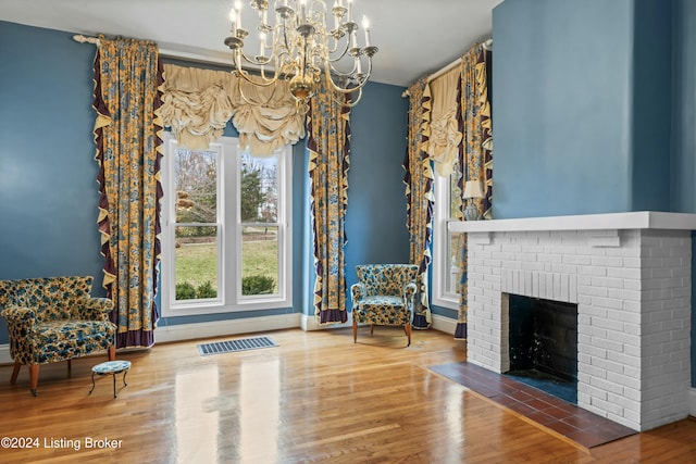 unfurnished room featuring a fireplace, wood-type flooring, an inviting chandelier, and plenty of natural light