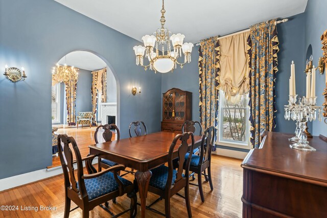 dining space with a fireplace, hardwood / wood-style flooring, and an inviting chandelier