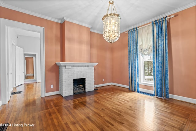 unfurnished living room featuring a brick fireplace, an inviting chandelier, ornamental molding, and hardwood / wood-style floors