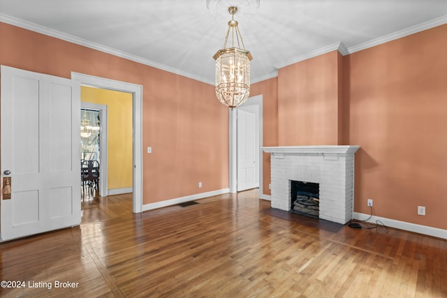 unfurnished living room featuring a fireplace, wood-type flooring, an inviting chandelier, and crown molding