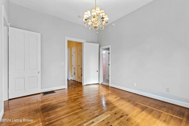 unfurnished bedroom featuring hardwood / wood-style floors and an inviting chandelier