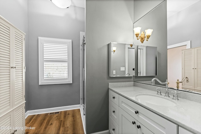 bathroom featuring hardwood / wood-style flooring, vanity, and a shower with door