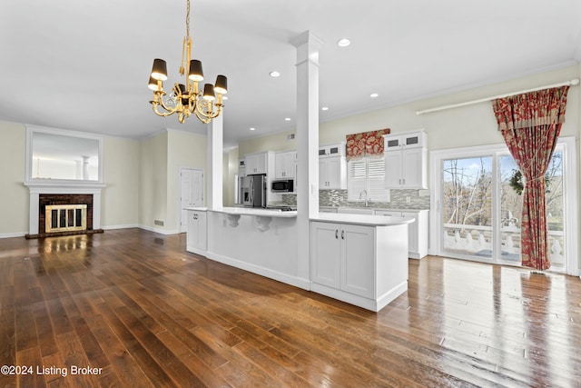 kitchen with white cabinets, stainless steel refrigerator with ice dispenser, a brick fireplace, and a chandelier