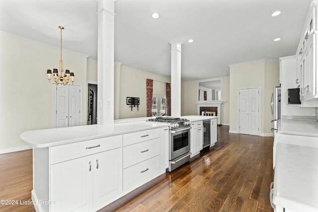 kitchen with stainless steel appliances, decorative columns, a chandelier, pendant lighting, and white cabinets