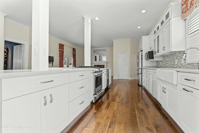 kitchen featuring tasteful backsplash, decorative columns, stainless steel appliances, dark hardwood / wood-style floors, and white cabinetry