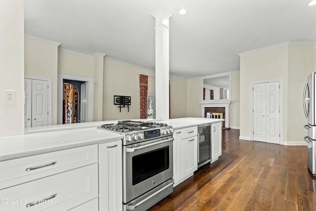 kitchen featuring a brick fireplace, white cabinetry, stainless steel appliances, beverage cooler, and decorative columns