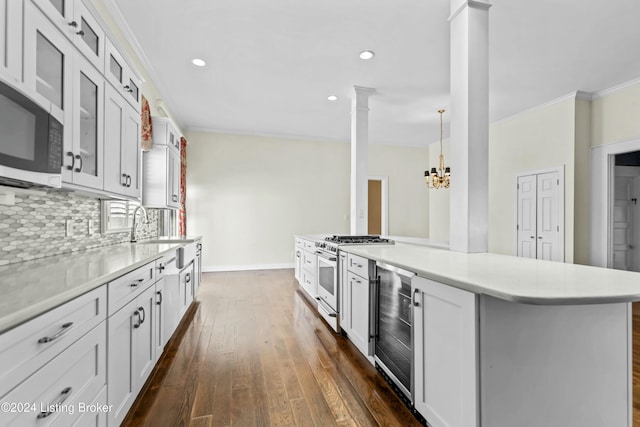 kitchen featuring ornate columns, white cabinetry, hanging light fixtures, beverage cooler, and stainless steel appliances