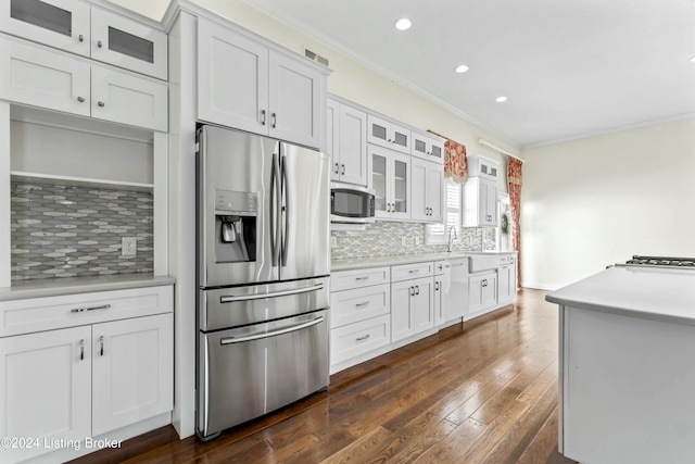 kitchen with backsplash, ornamental molding, stainless steel appliances, dark wood-type flooring, and white cabinetry