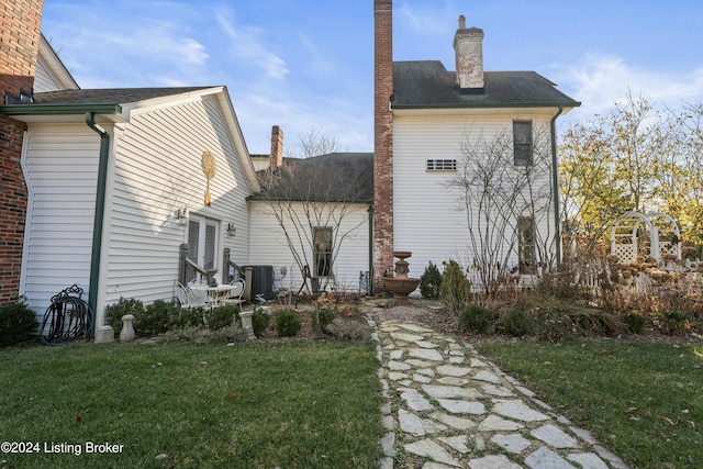 rear view of property with central AC and a lawn