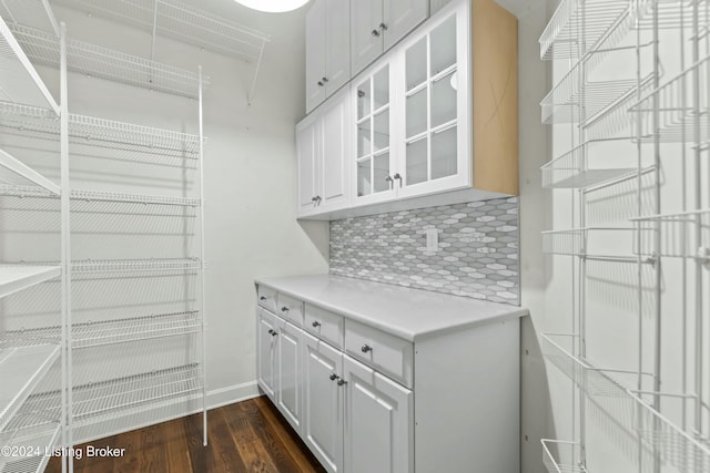 bar with decorative backsplash, dark hardwood / wood-style flooring, and white cabinets