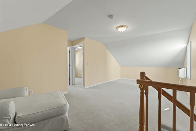 additional living space with light colored carpet and vaulted ceiling