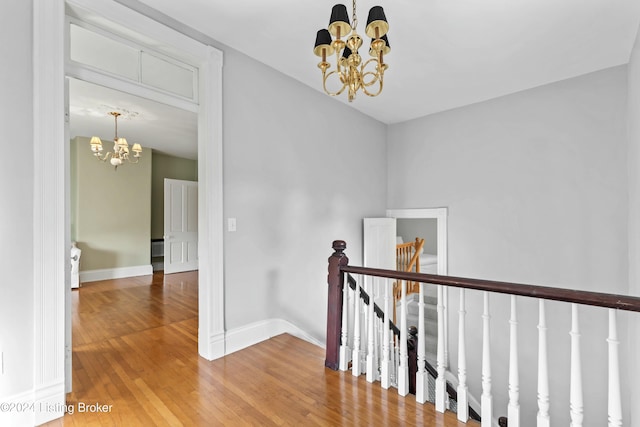 hallway with hardwood / wood-style floors and an inviting chandelier