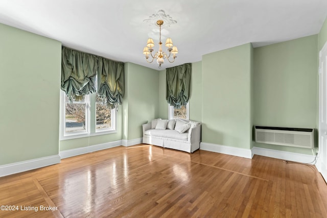 unfurnished room featuring a wall mounted AC, hardwood / wood-style flooring, and an inviting chandelier