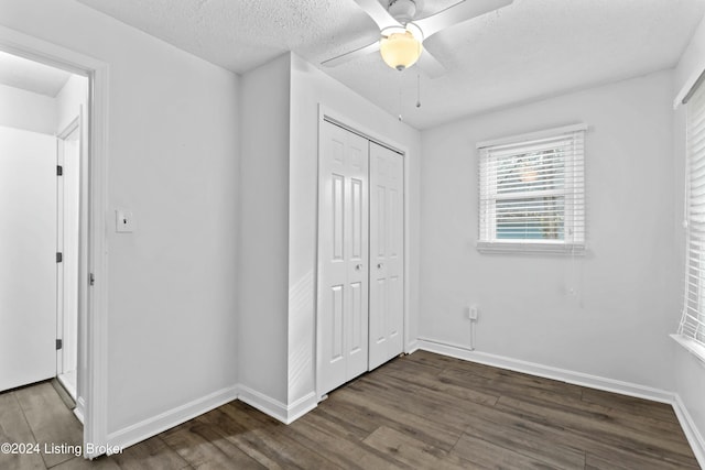 unfurnished bedroom featuring ceiling fan, dark hardwood / wood-style flooring, a textured ceiling, and a closet