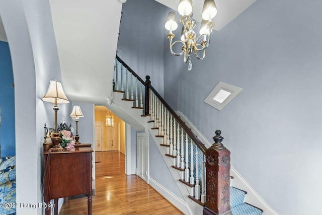 stairway with wood-type flooring and an inviting chandelier