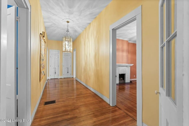 corridor with hardwood / wood-style floors and an inviting chandelier