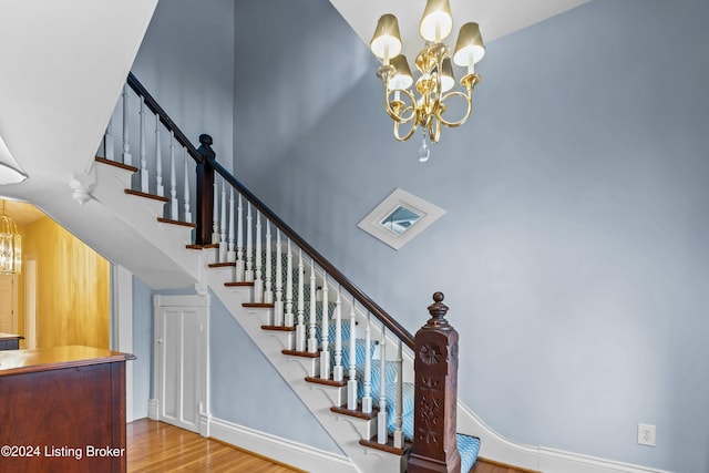 staircase with hardwood / wood-style floors and an inviting chandelier