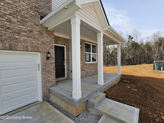 entrance to property with a porch, an attached garage, and brick siding