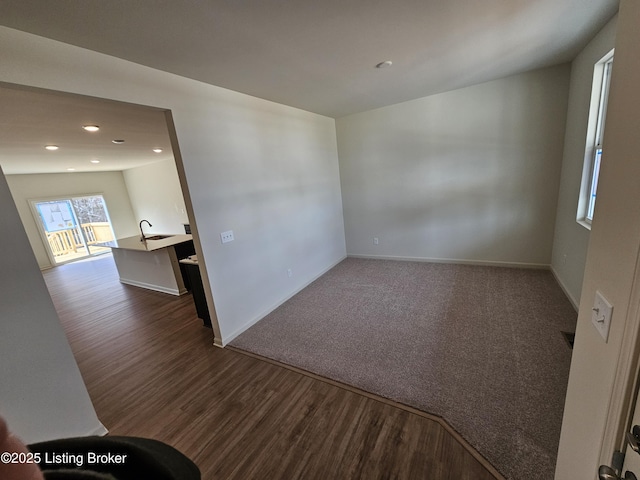 spare room with a sink, baseboards, wood finished floors, and recessed lighting