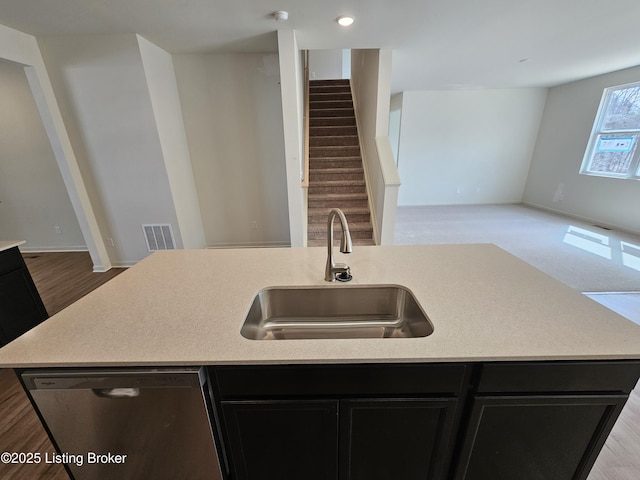 kitchen with light countertops, visible vents, stainless steel dishwasher, and dark cabinetry