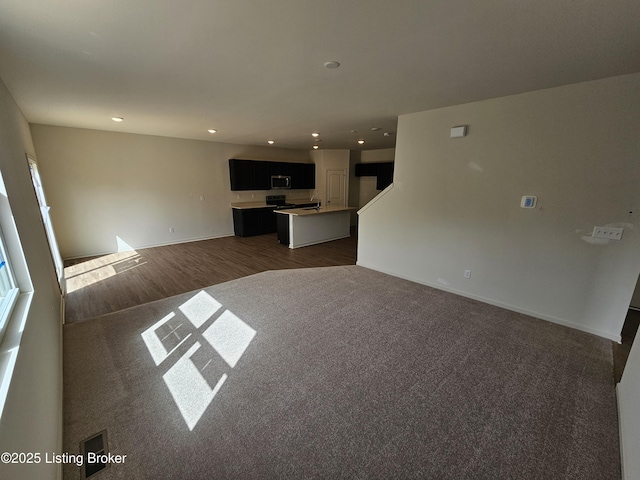 unfurnished living room with baseboards, dark wood finished floors, and recessed lighting