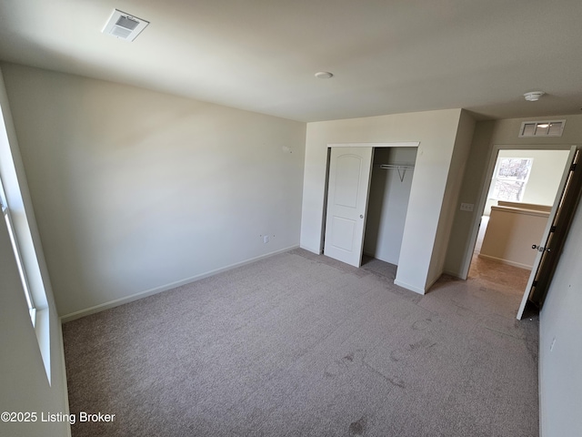 unfurnished bedroom featuring a closet, carpet flooring, visible vents, and baseboards