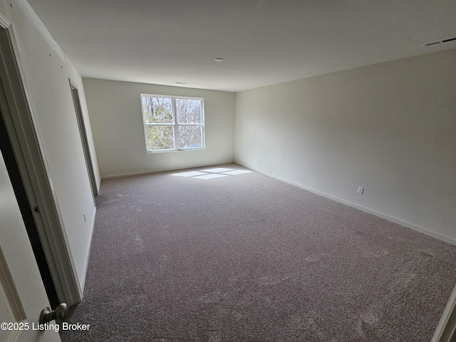 unfurnished room featuring carpet, visible vents, and baseboards